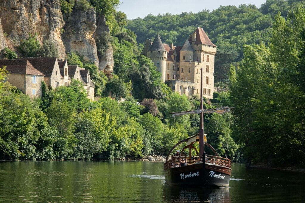 Charming boat on Dordogne River near a medieval castle in Nouvelle-Aquitaine, France.