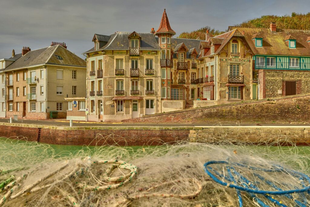 Historic waterfront houses in Fécamp, Normandy, with fishing nets in the foreground.