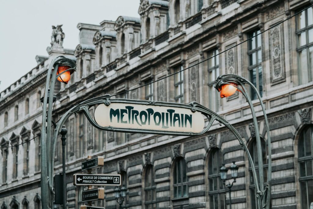Paris Métro entrance with iconic art nouveau design in front of historic architecture.