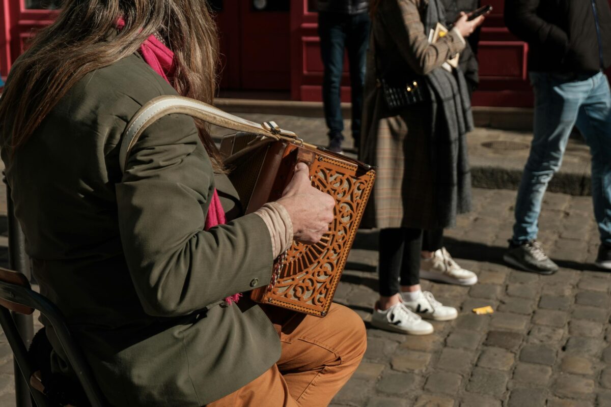 Street artist playing accordion on a cobblestone street in Paris, capturing an authentic urban scene.