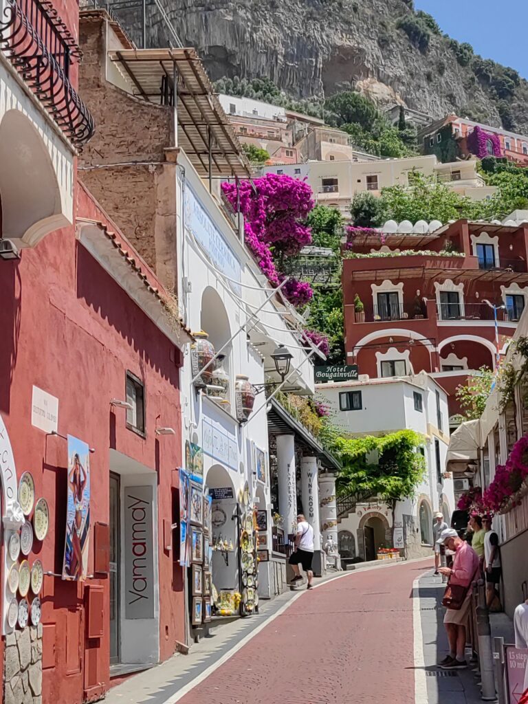Picturesque street scene in Positano, Italy with colorful buildings and blooming flowers on a sunny day.